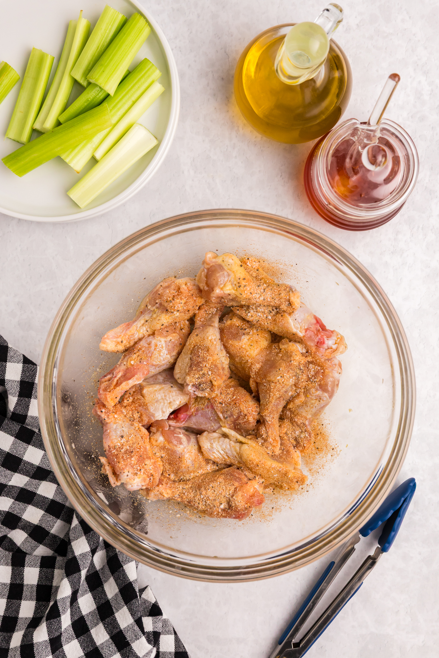 Raw chicken wings in a bowl coated with dry seasoning mix.