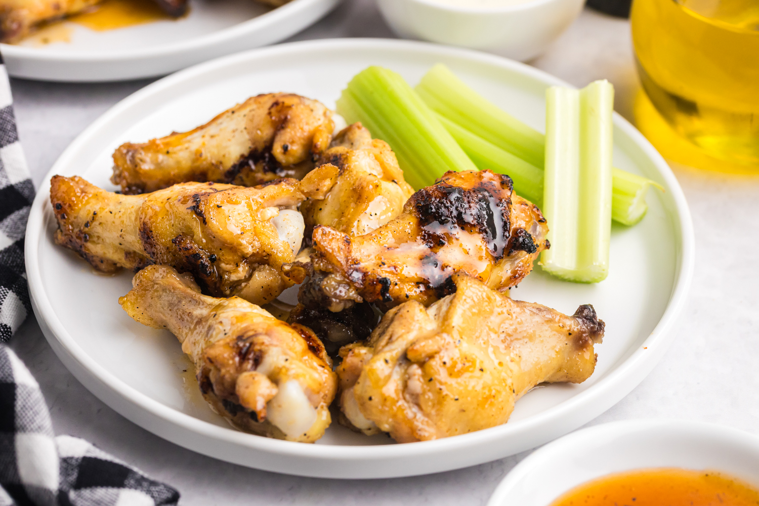 Plate of grilled hot honey chicken wings served with celery sticks on the side.