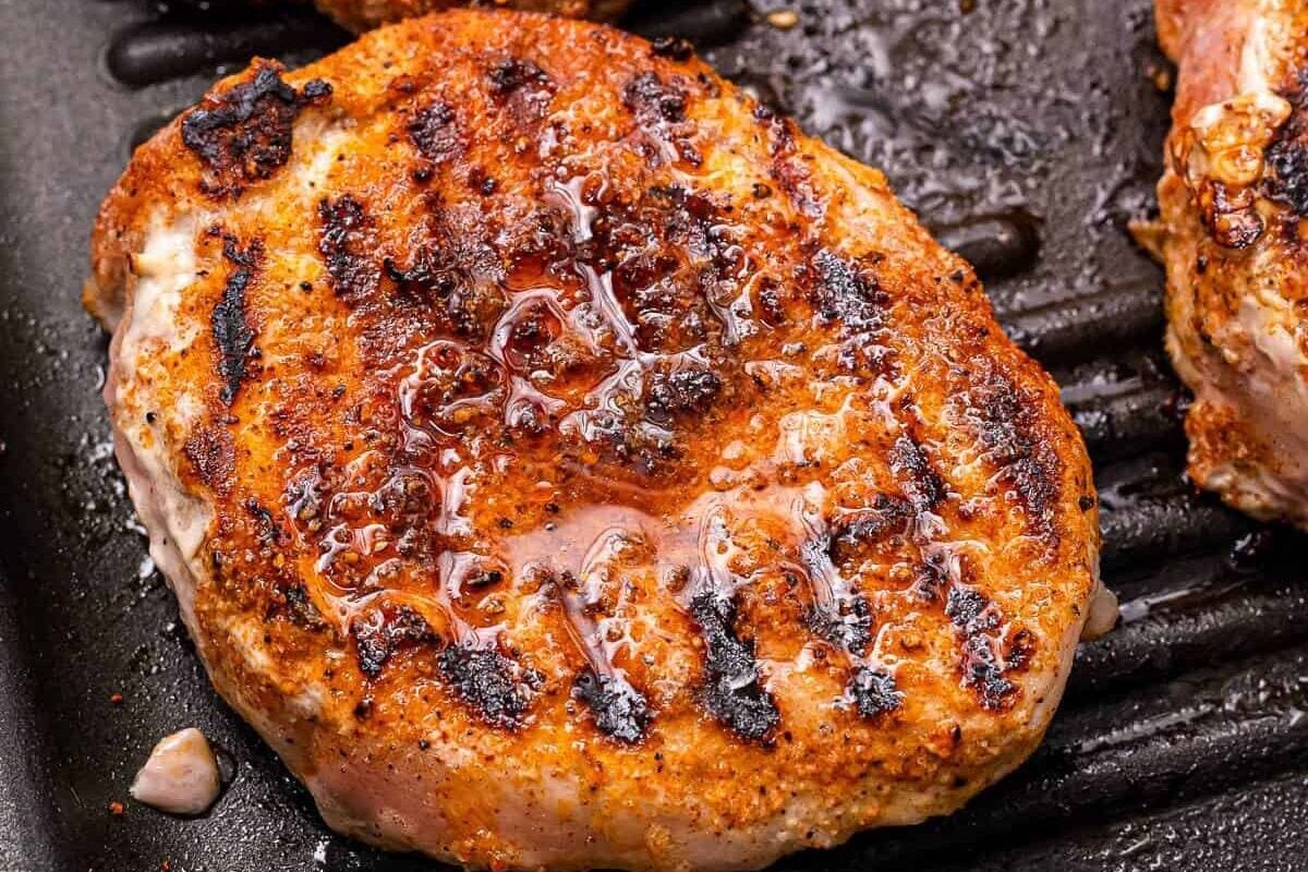 A grill pan with seasoned pork chops on it