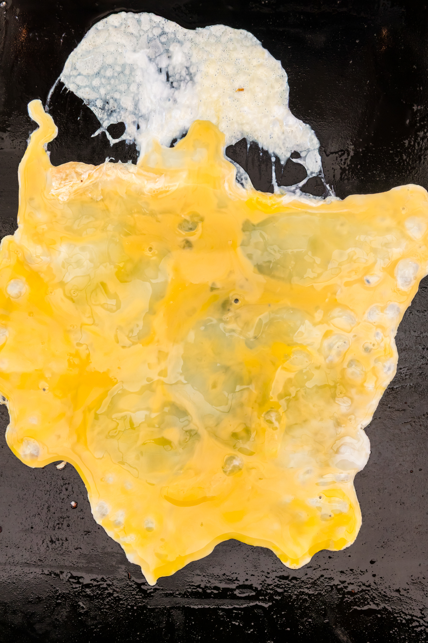 Beaten eggs cooking and beginning to set on a griddle.