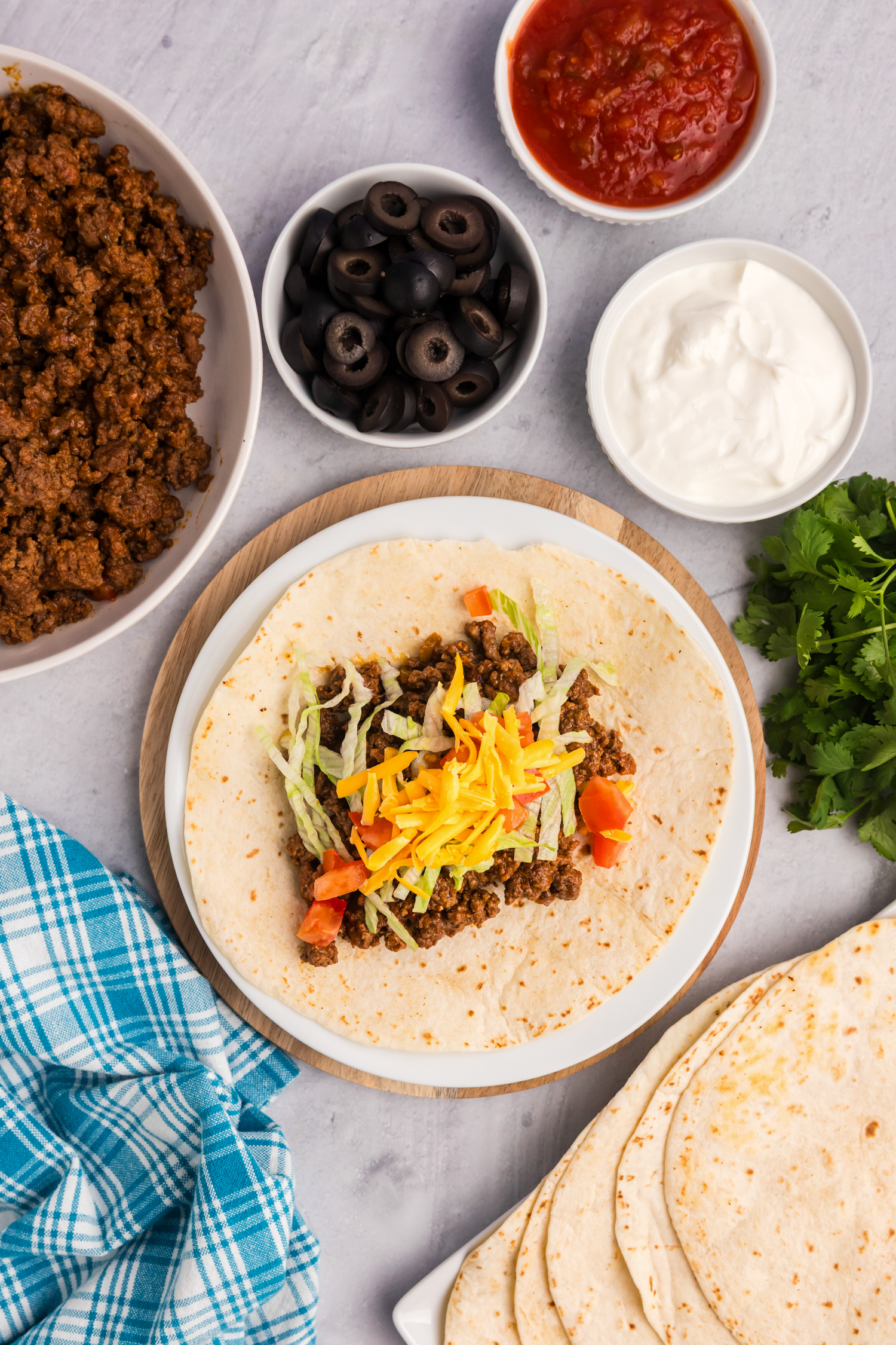 Raw ground beef sizzling on a hot griddle, beginning to brown as it cooks.