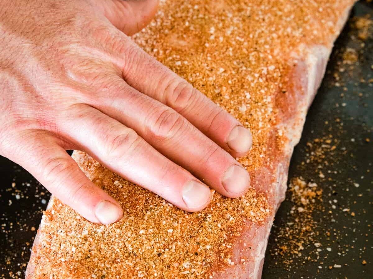 Hand rubbing dry rub on pork loin