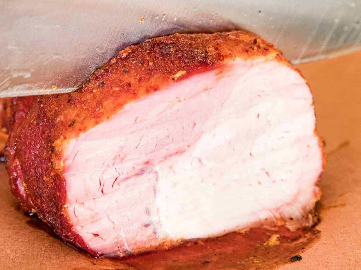 Knife cutting a piece of smoked pork loin off