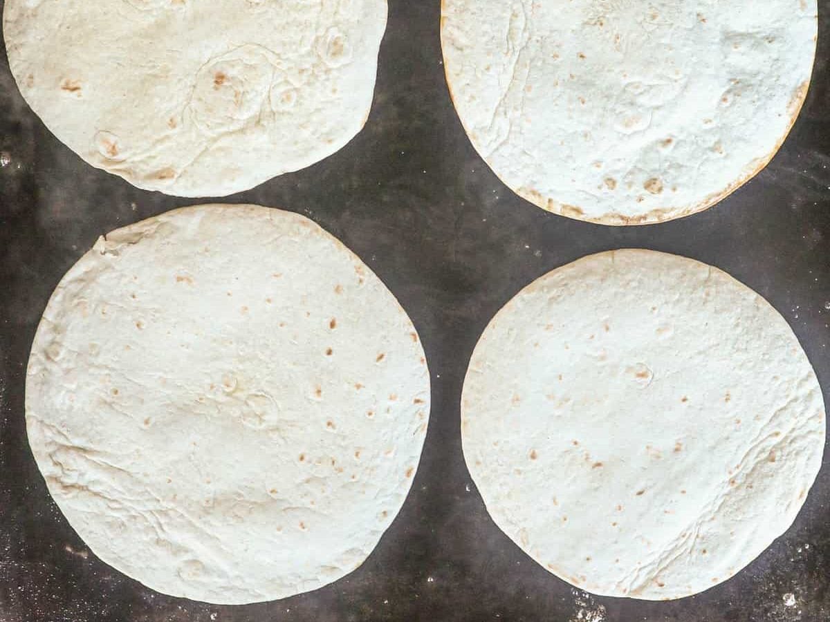 Beef and tortillas face down on buttered Blackstone griddle for Smash Burger Tacos