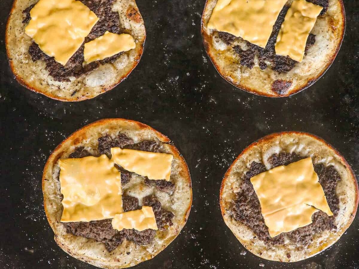 Adding cheese to Smash Burger Tacos on Blackstone