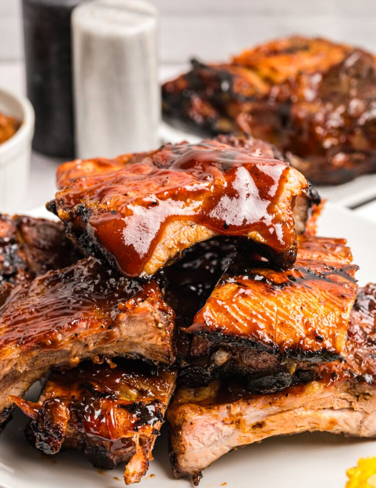 Close-up of tender grilled pork ribs coated in a thick layer of glossy barbecue sauce and stacked on a serving platter.
