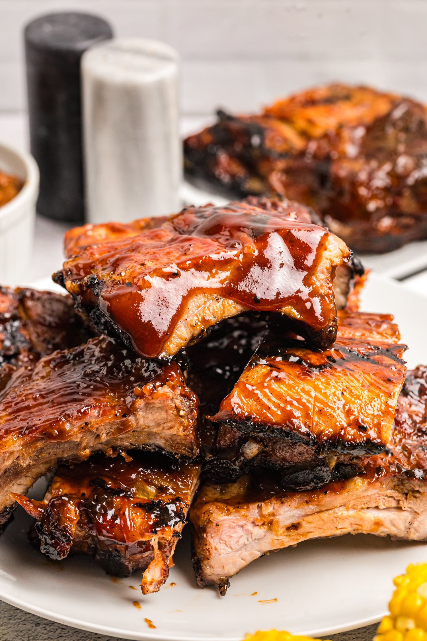 Close-up of tender grilled pork ribs coated in a thick layer of glossy barbecue sauce and stacked on a serving platter.