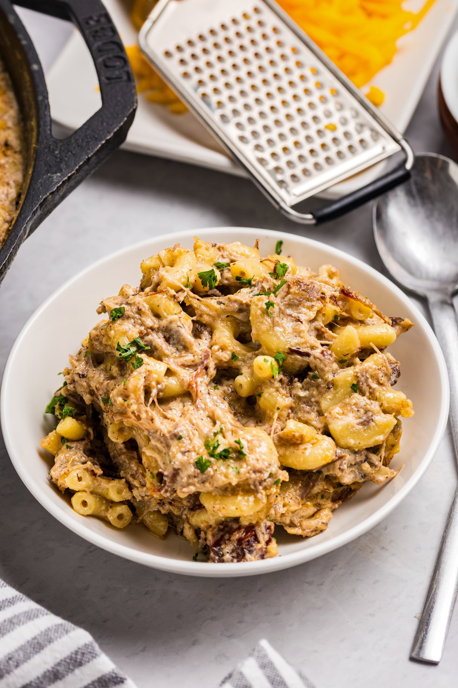 Creamy smoked brisket mac and cheese topped with shredded cheese and fresh parsley.