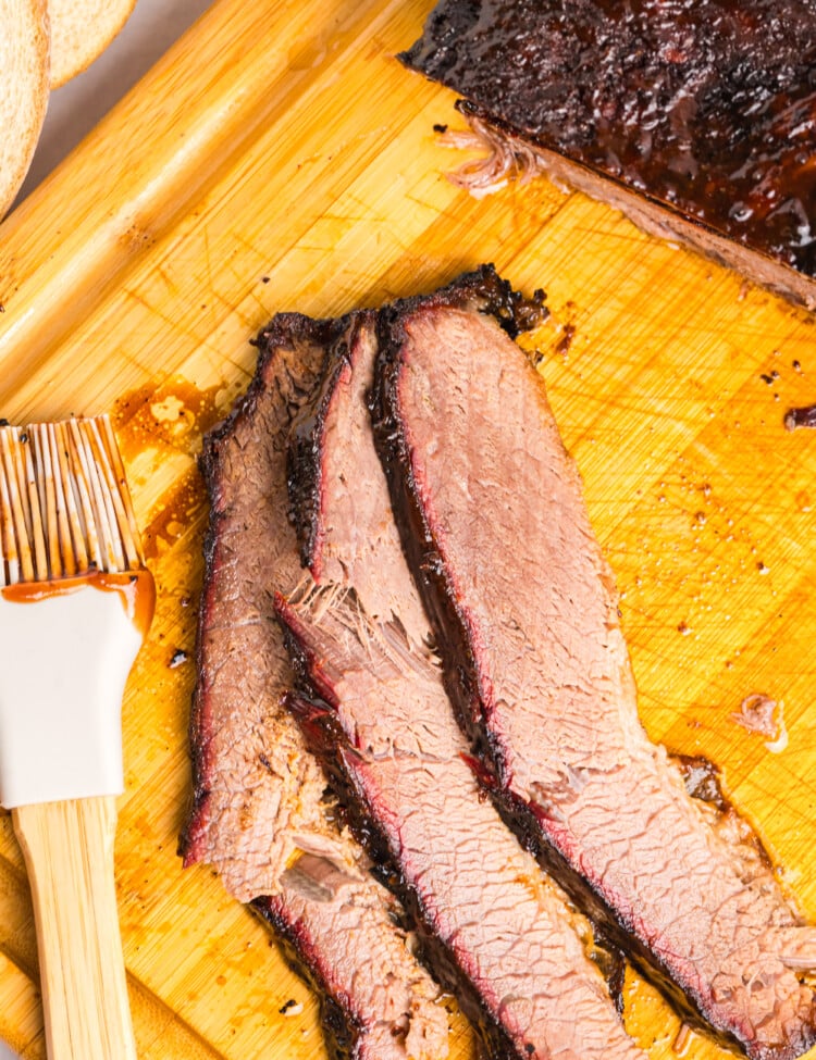 Tender smoked brisket sliced on a cutting board with a dark bark and smoke ring.