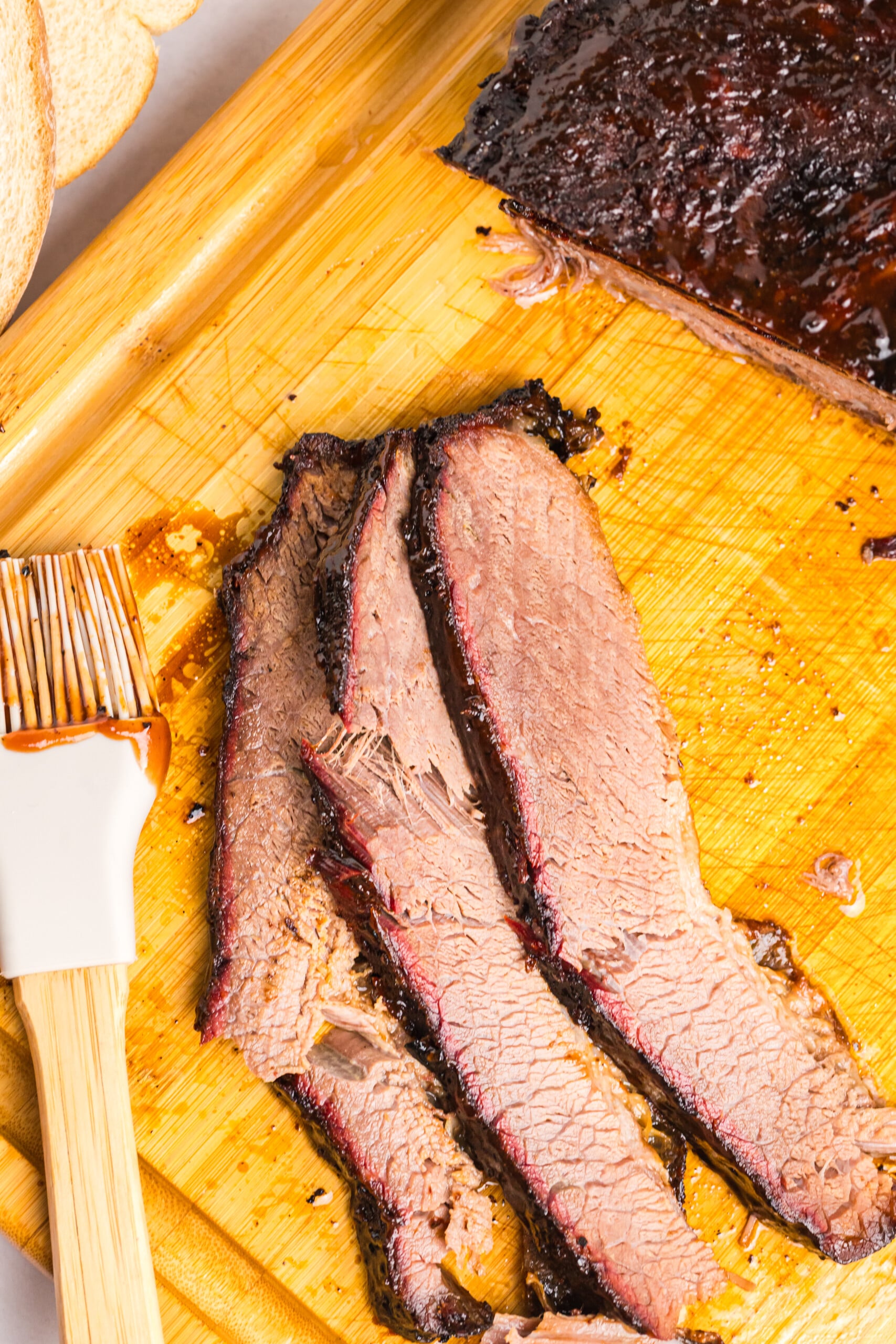 Tender smoked brisket sliced on a cutting board with a dark bark and smoke ring.
