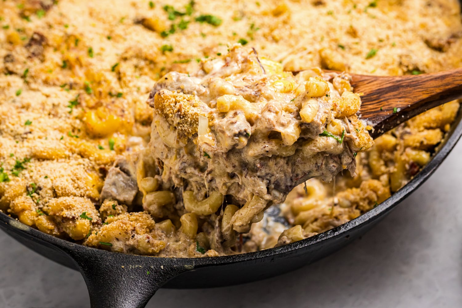 Creamy brisket mac and cheese with a golden breadcrumb topping served from a cast iron skillet.