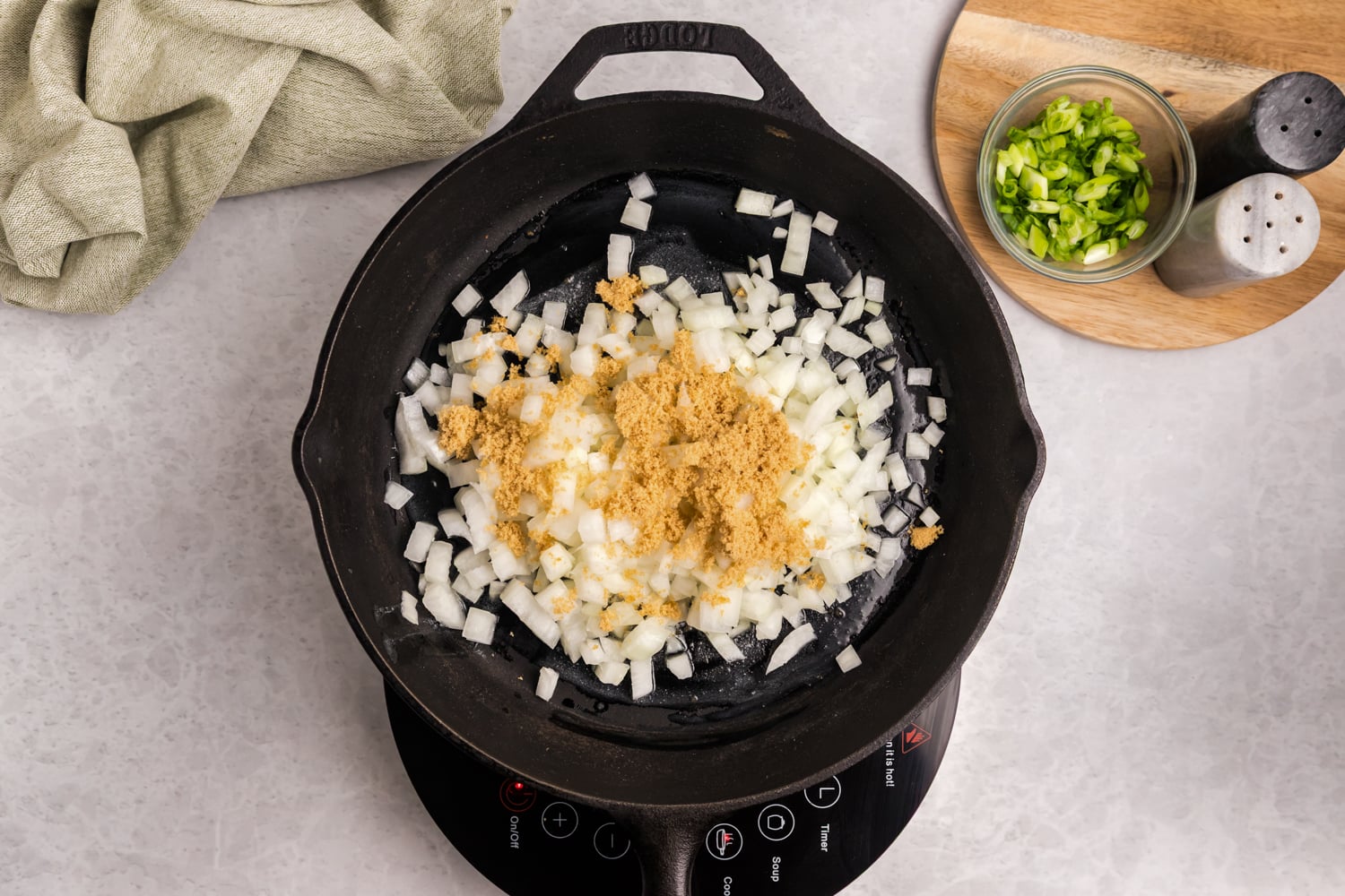 Diced onions and seasonings cooking in a cast iron skillet.