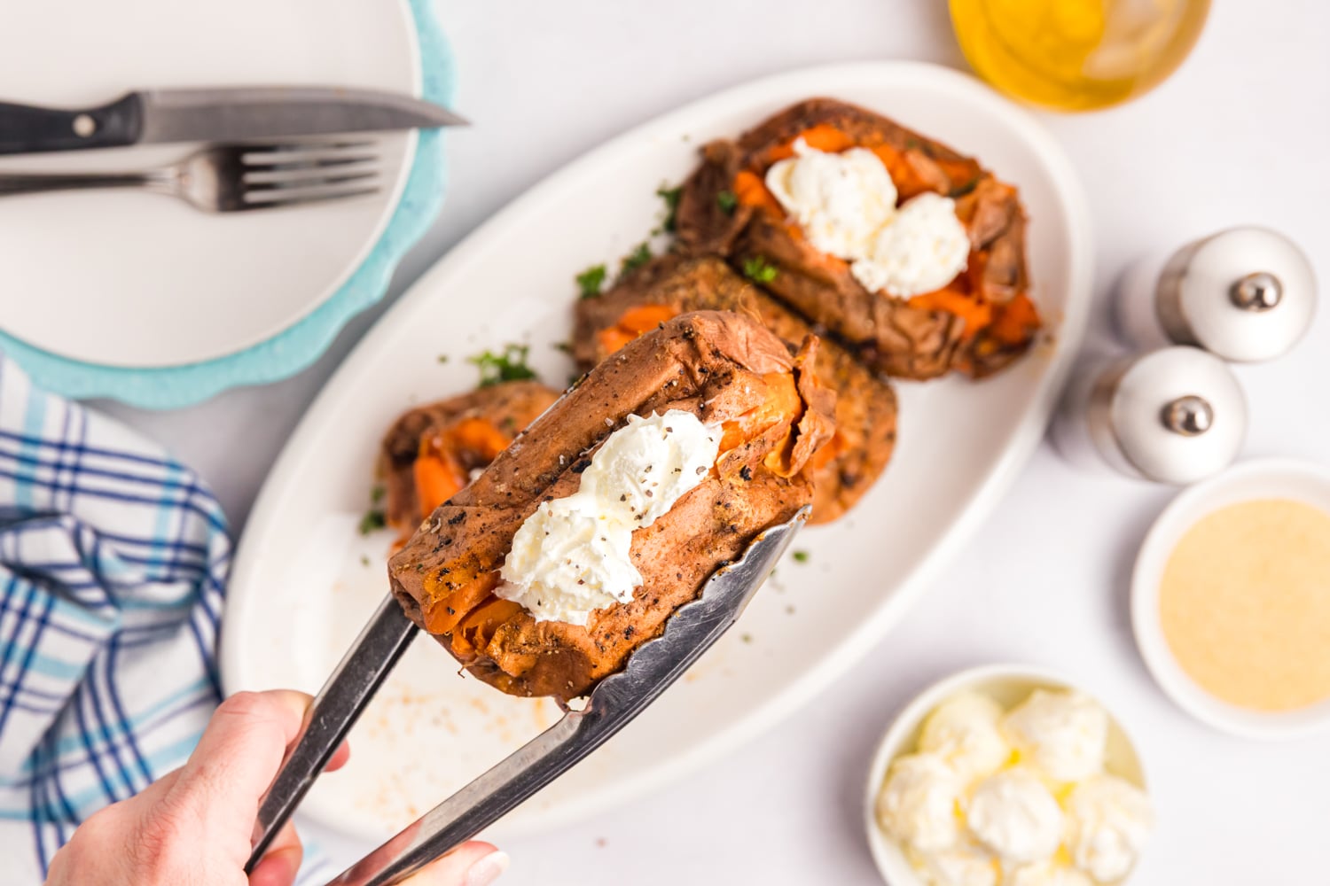 Smoked sweet potato topped with butter being lifted from a serving platter.